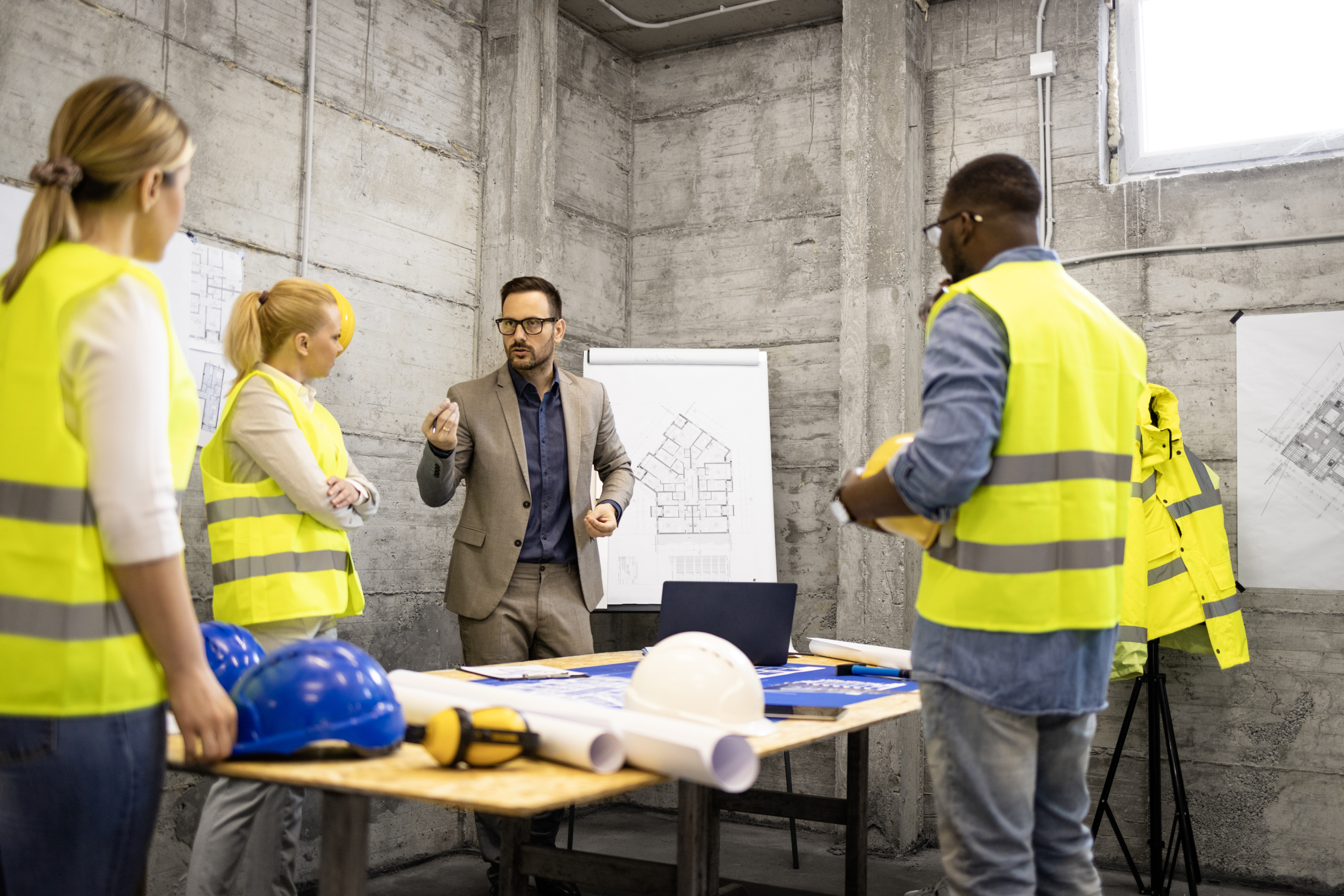Team of structural engineers and architects having a meeting at construction site analyzing structure plant or blueprint.
